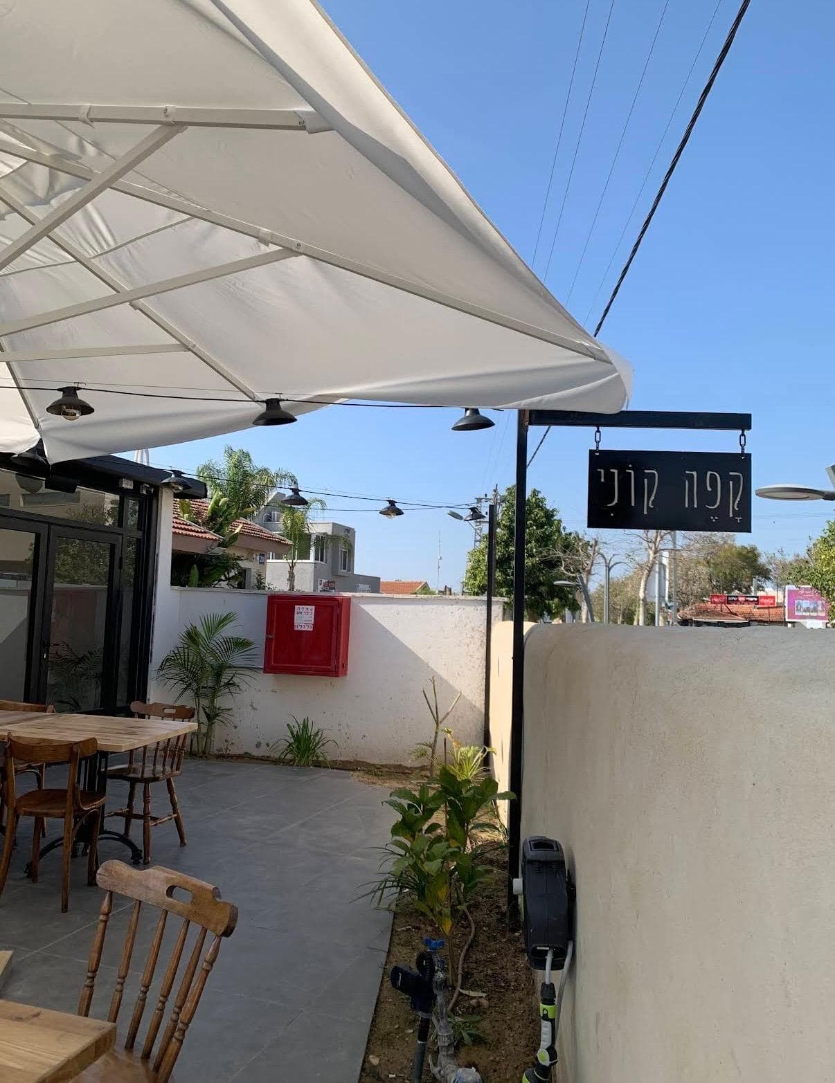 קפה קוני אופקים — חצר בית הקפה עם השלט והפרגולה