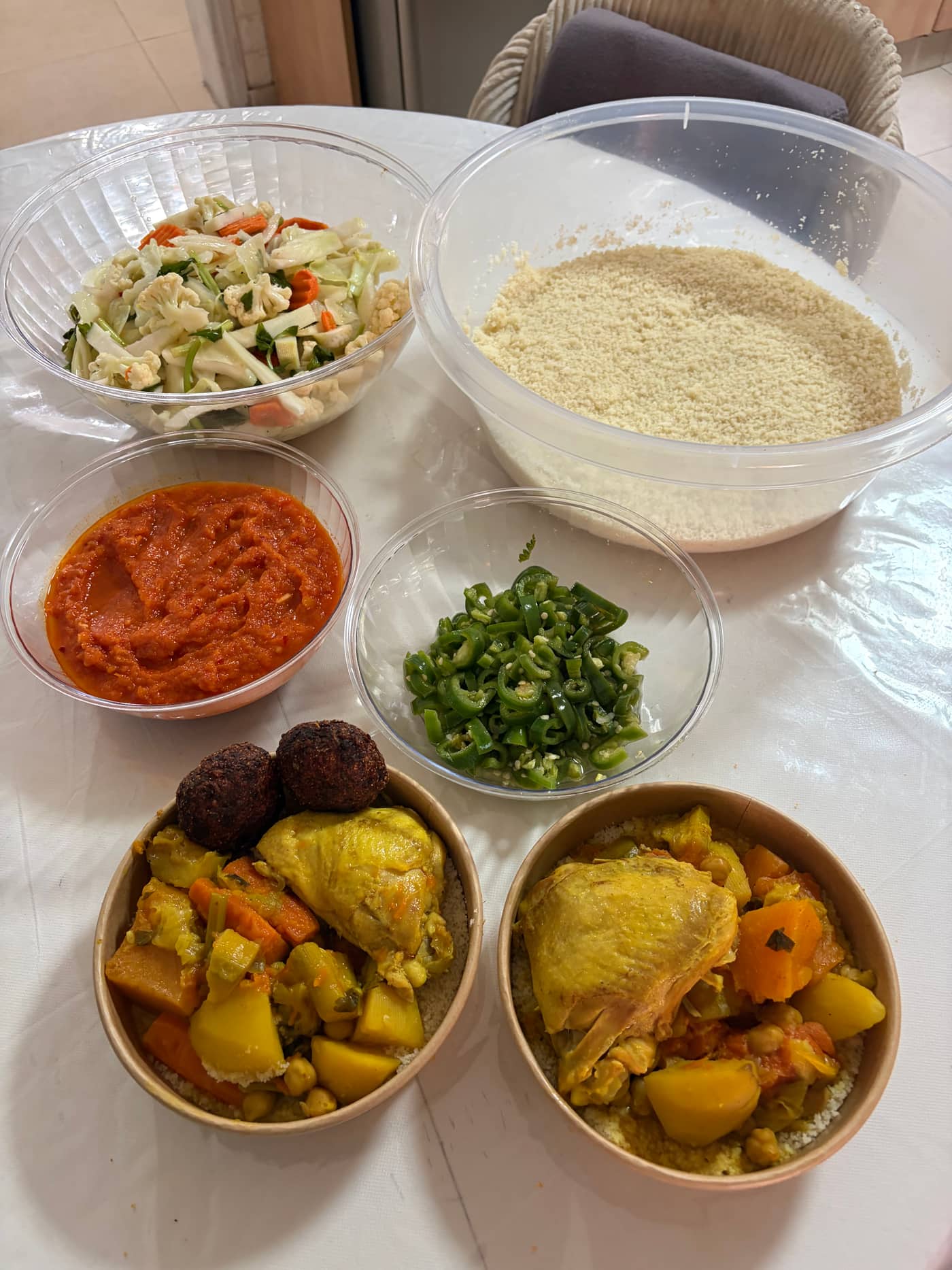 הסט המלא של הקוסקוס של אביגייל — גרגירי קוסקוס, מרק, חריף, סלט ירקות ורוטב אדום לצד קערות עוף