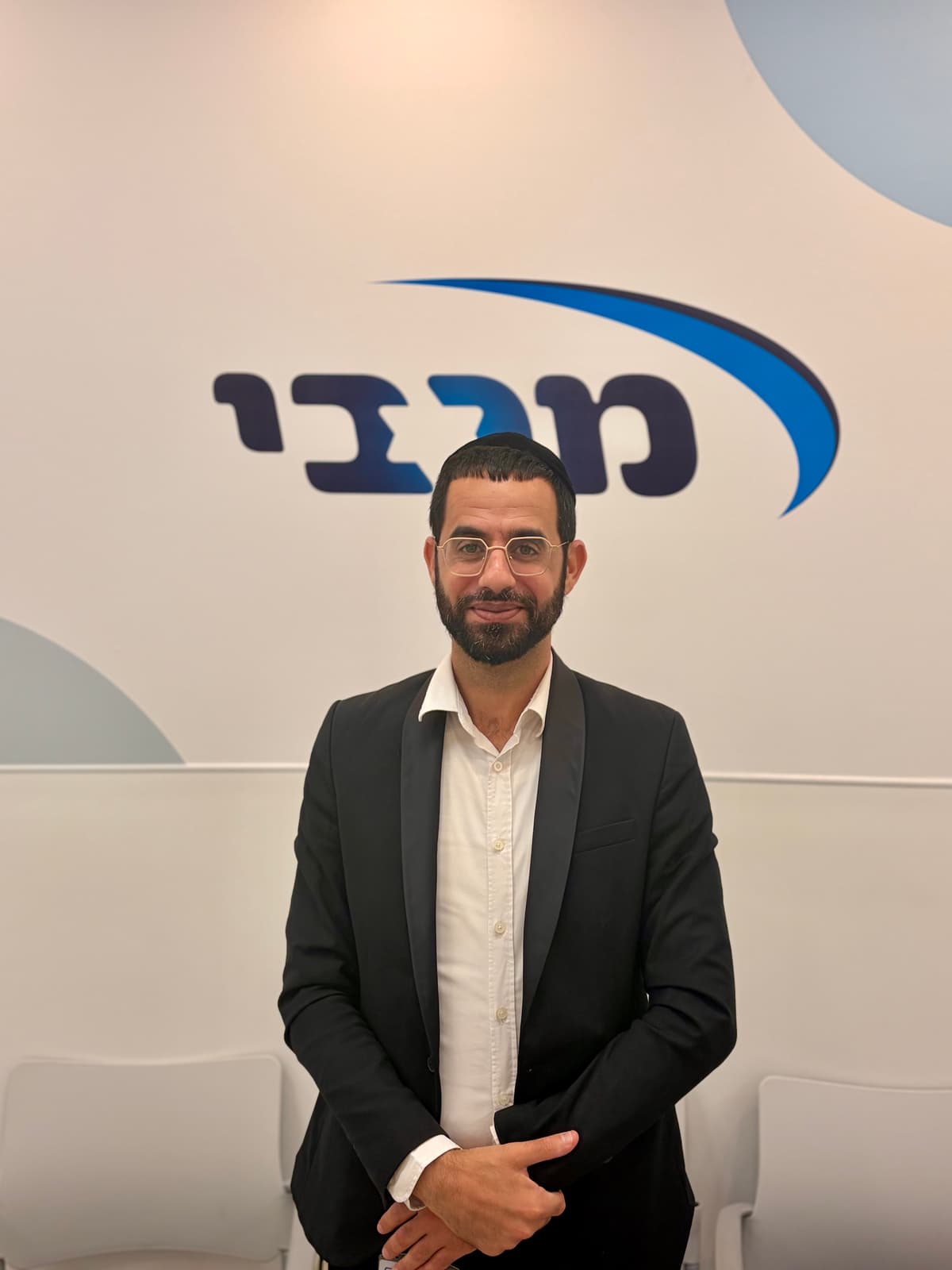 ינון מצליח על רקע לוגו מכבי שירותי בריאות