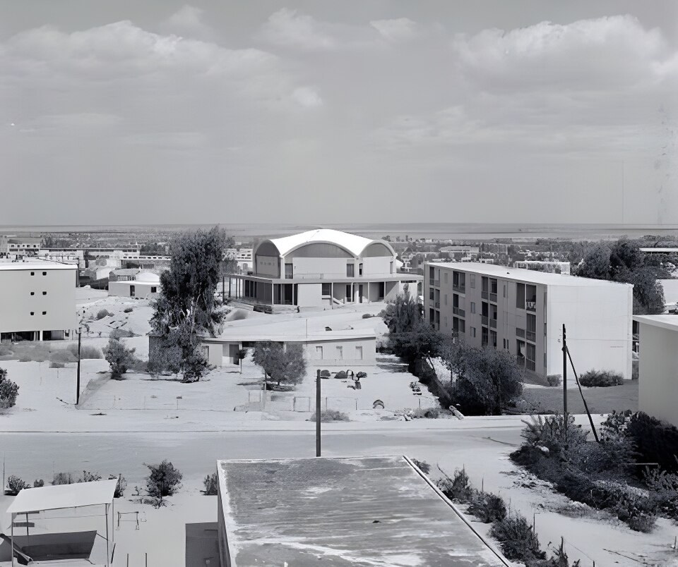 מבנה ישיבת אופקים בשנותיה הראשונות — צילום שחור-לבן של המבנה המקומר על רקע העיר הצעירה